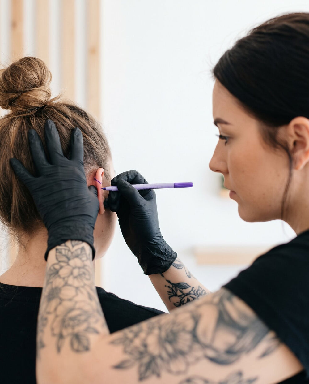 Piercer marking the spot on the ear